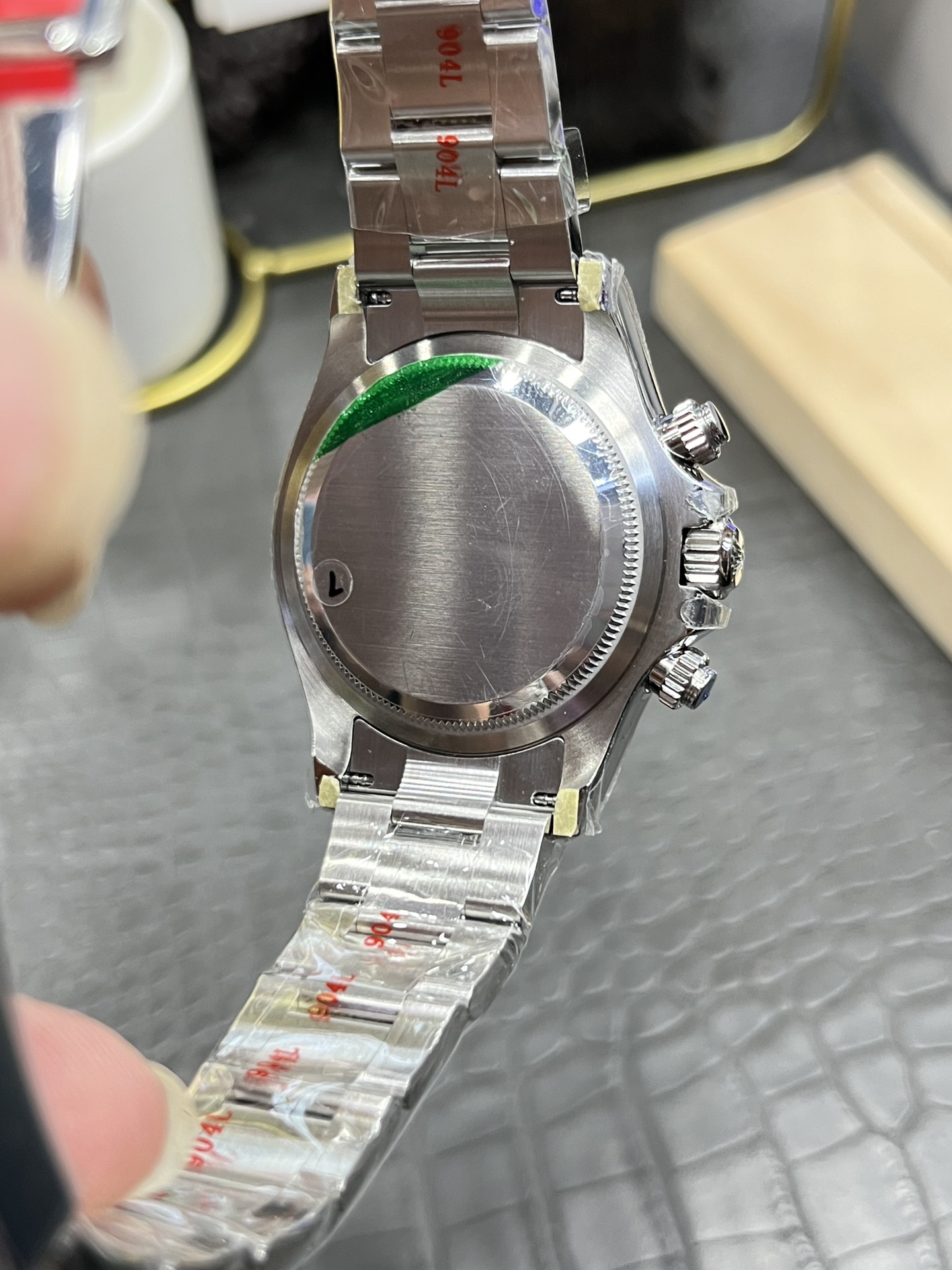 Rolex Cosmograph Daytona M126500ln showing brushed steel finish and green protective sticker.