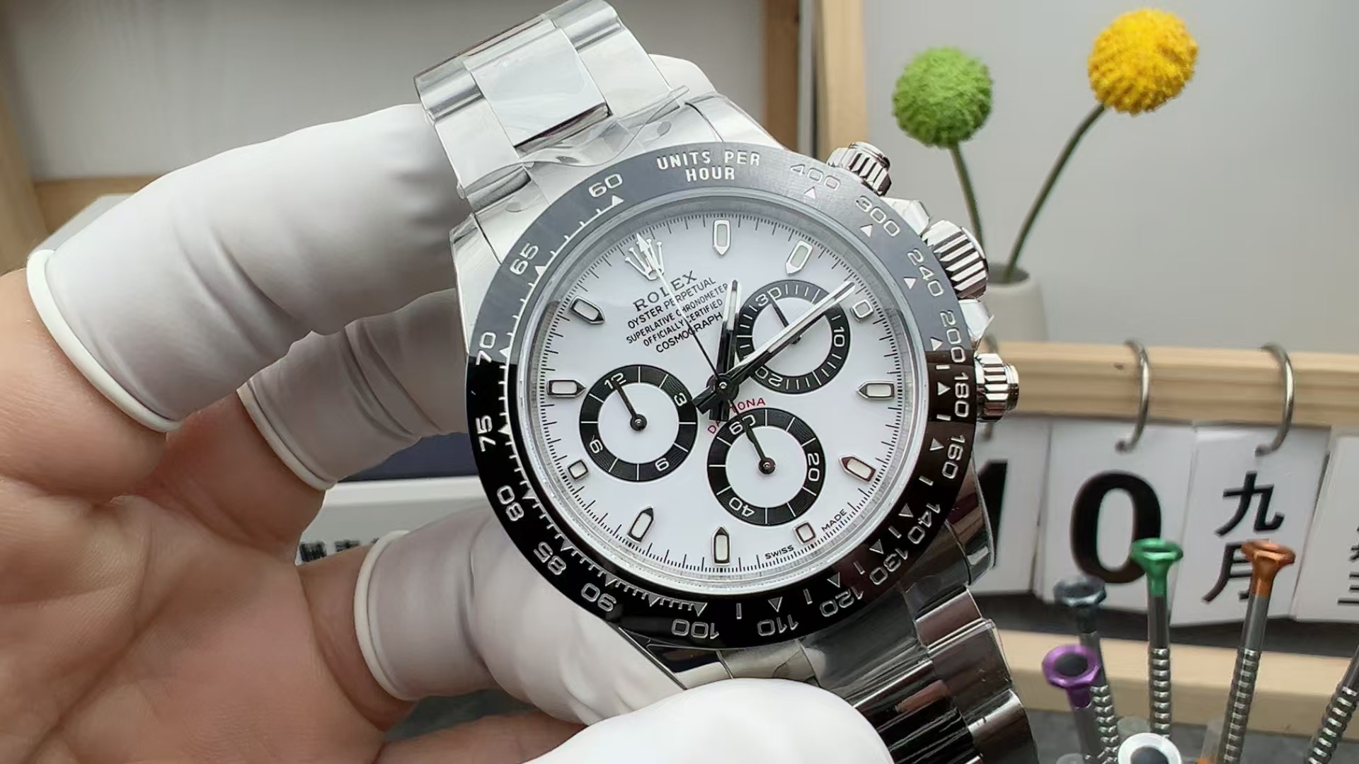 Front view of the Rolex Cosmograph Daytona 116500LN with white dial and black ceramic bezel, held by gloved hand.