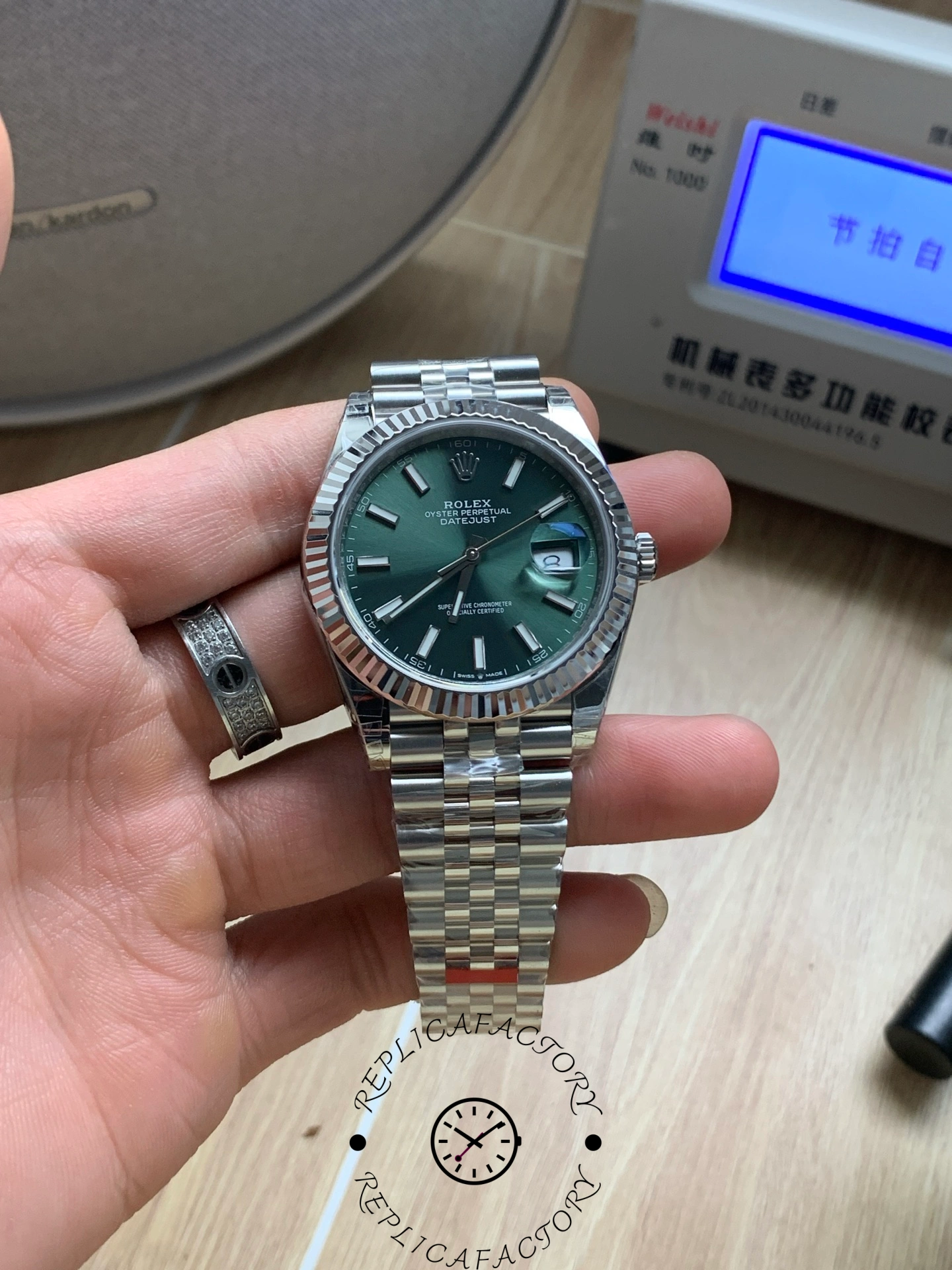 Hand-held view of Rolex Datejust 126334 VS with green dial and fluted bezel.