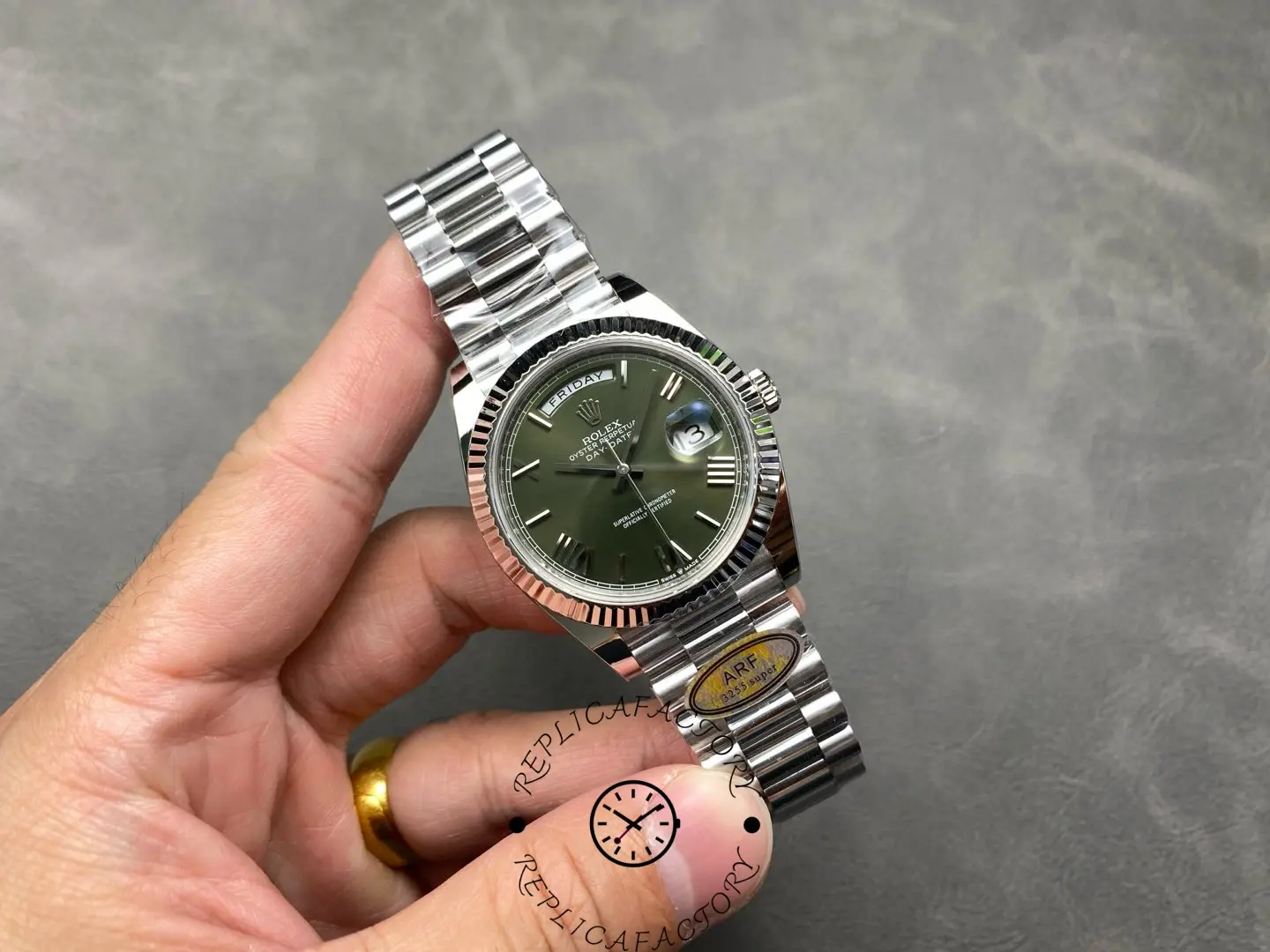 Full view of Rolex Day-Date 228239 with green dial held in hand showing bracelet and bezel.