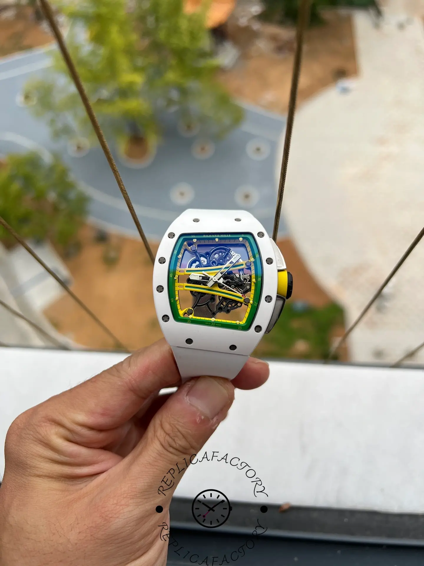 Handheld image of RM61-01 replica highlighting the white ceramic case and openworked movement.