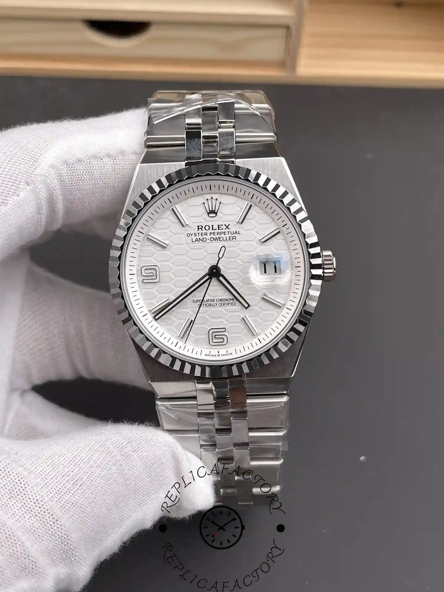 Front view of the Rolex Land-Dweller M127334-0001 with white honeycomb dial, fluted bezel, and Jubilee bracelet held by gloved hand.