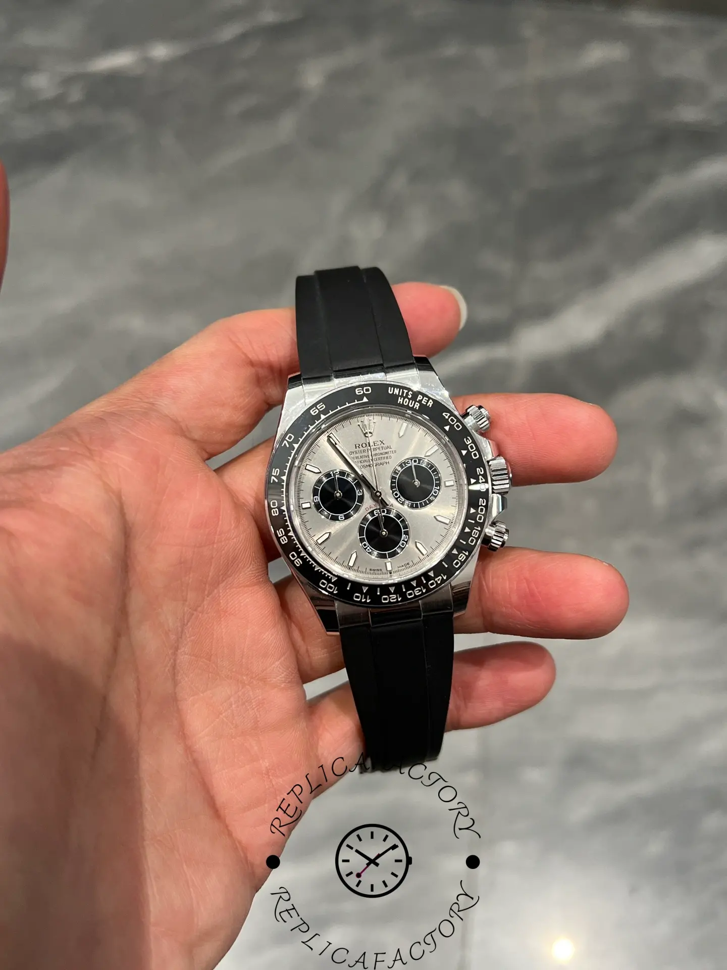 Close-up of Rolex Daytona 126519LN showing silver dial, black subdials, and Oysterflex strap held in hand.
