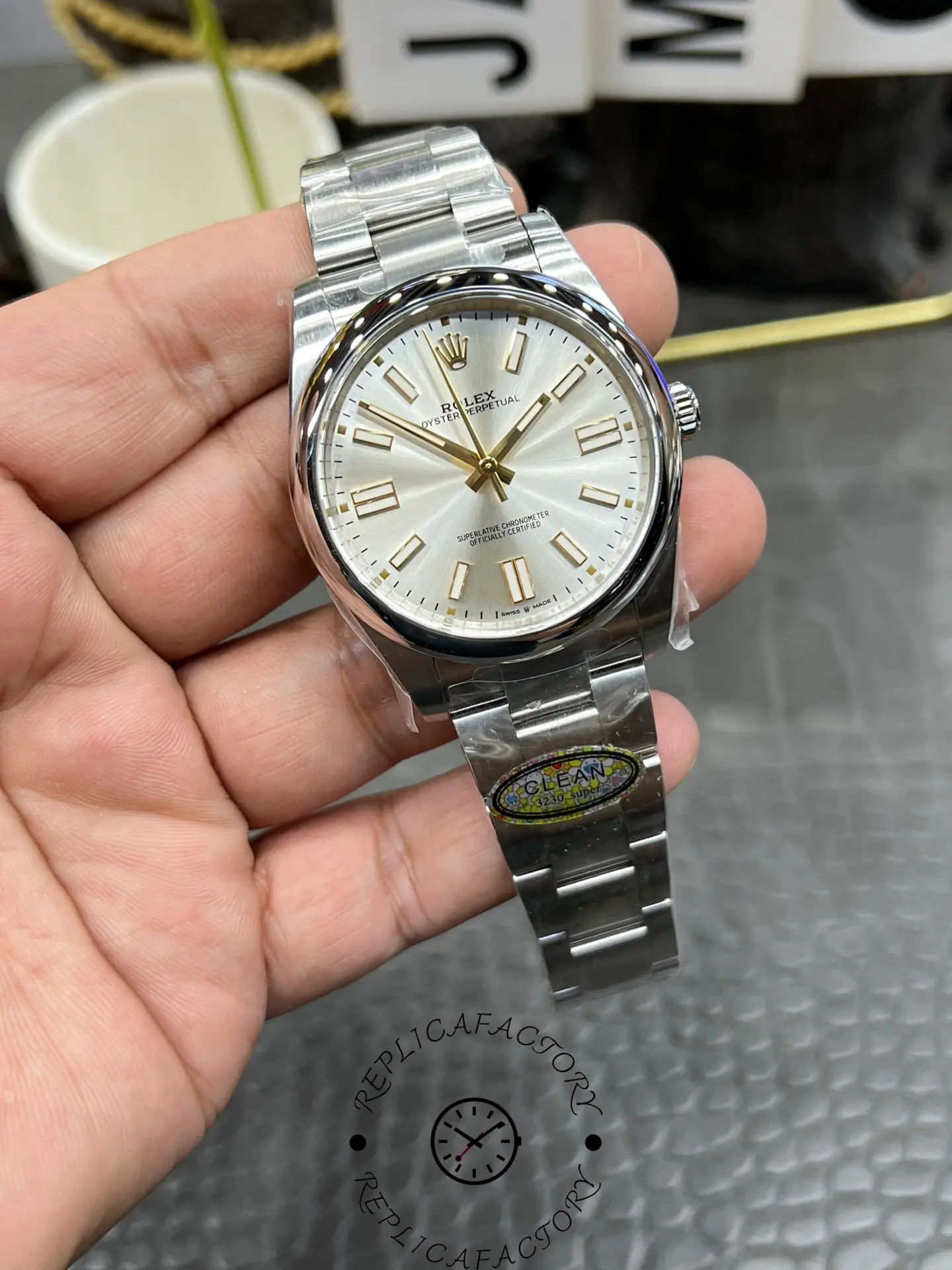 Close-up of Rolex replica M124300-0001 dial with gold markers and silver sunburst finish.