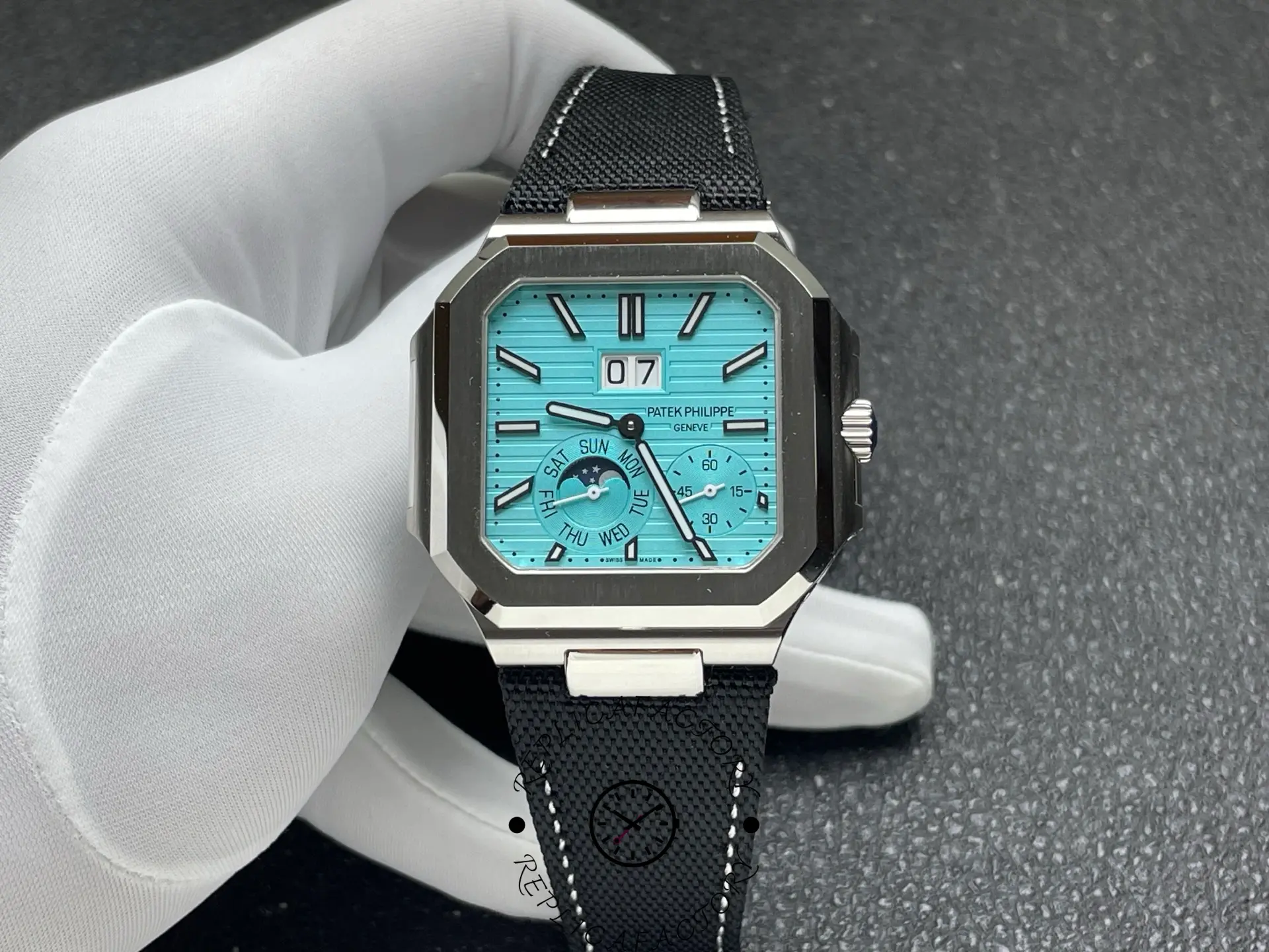 Handheld shot of Patek Philippe 5822P replica with Tiffany blue dial and black strap.