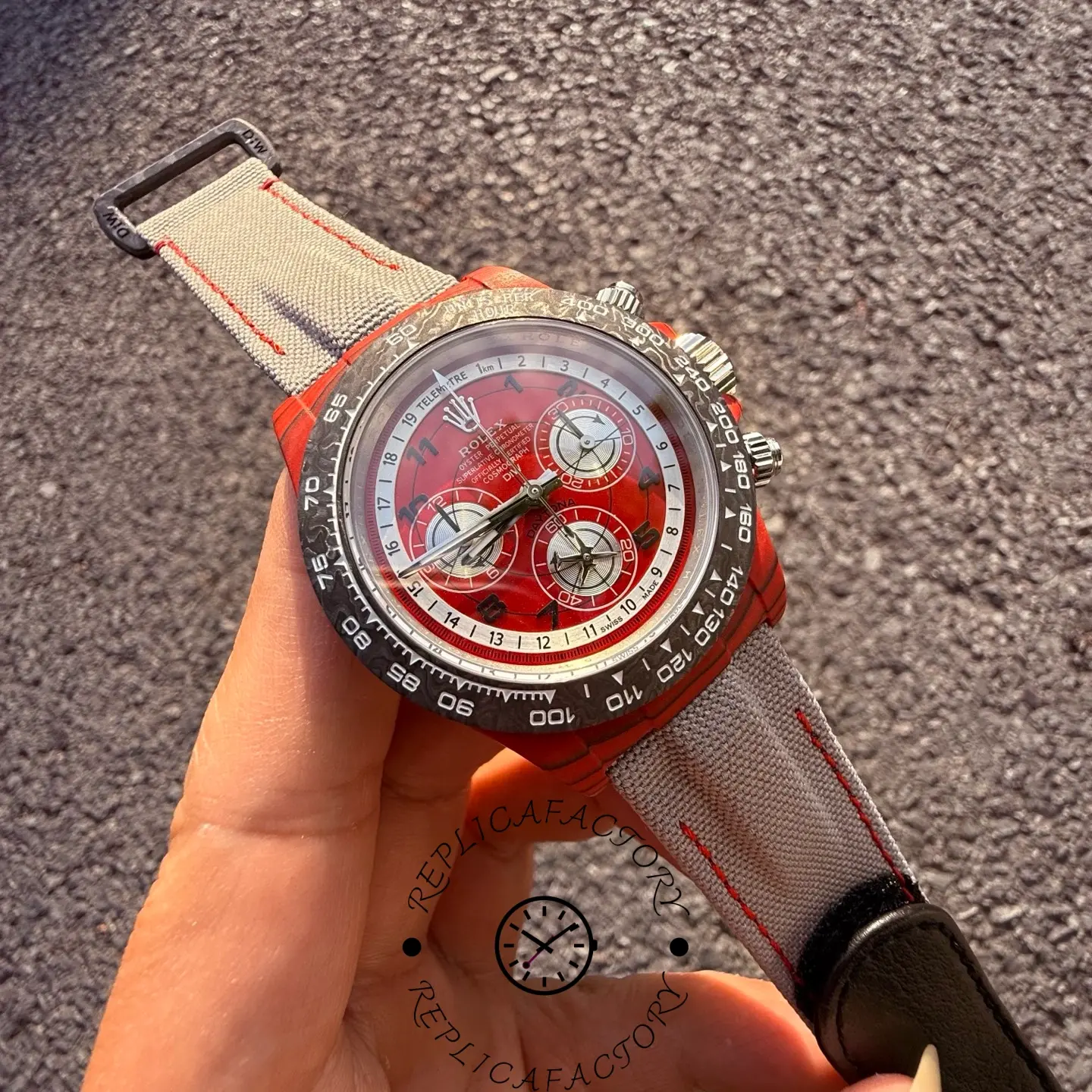 Angled front view of the Rolex Daytona DiW showing red dial, carbon bezel markings and chronograph pushers.
