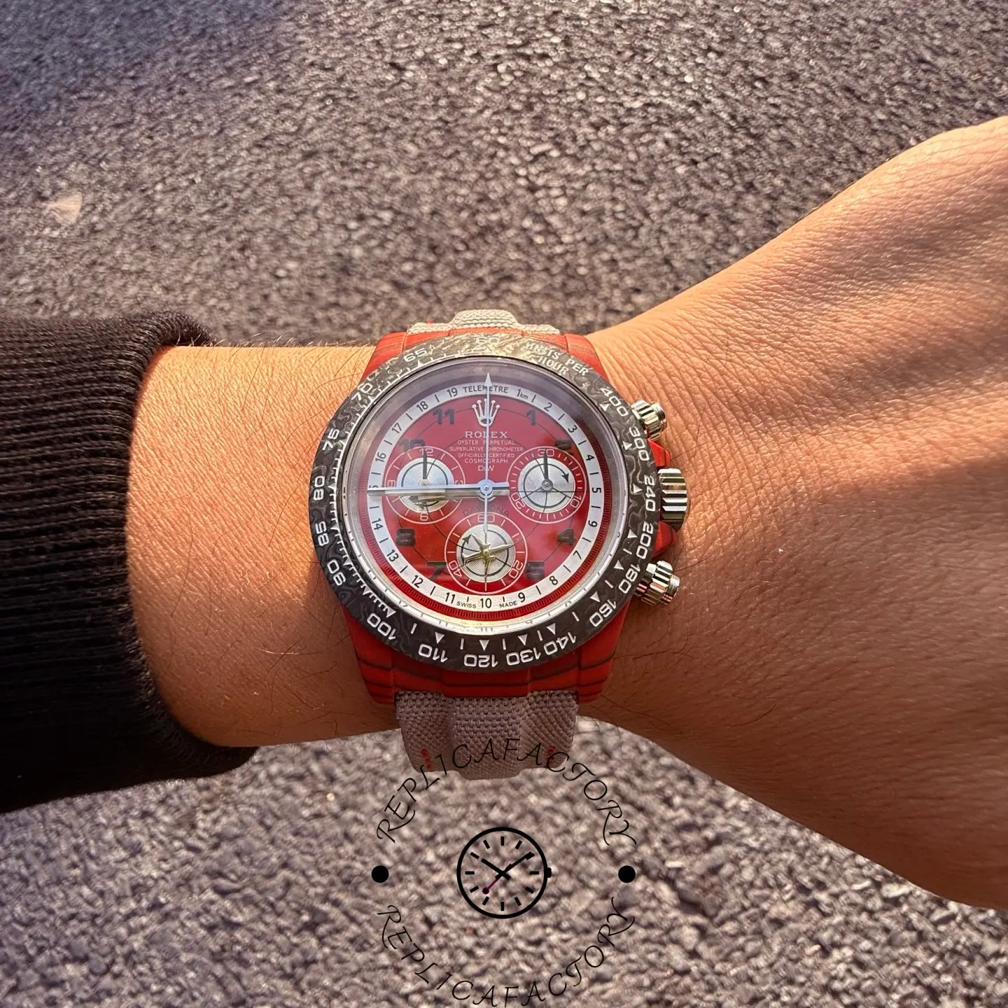 Wrist shot of the Rolex Daytona DiW carbon case with red dial worn on grey fabric strap.