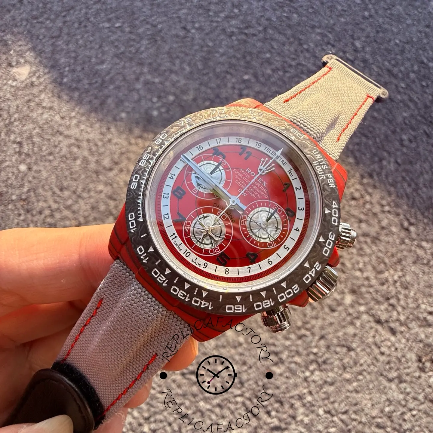 Close-up angled view of the Rolex Daytona DiW red dial with three silver subdials and tachymeter bezel.