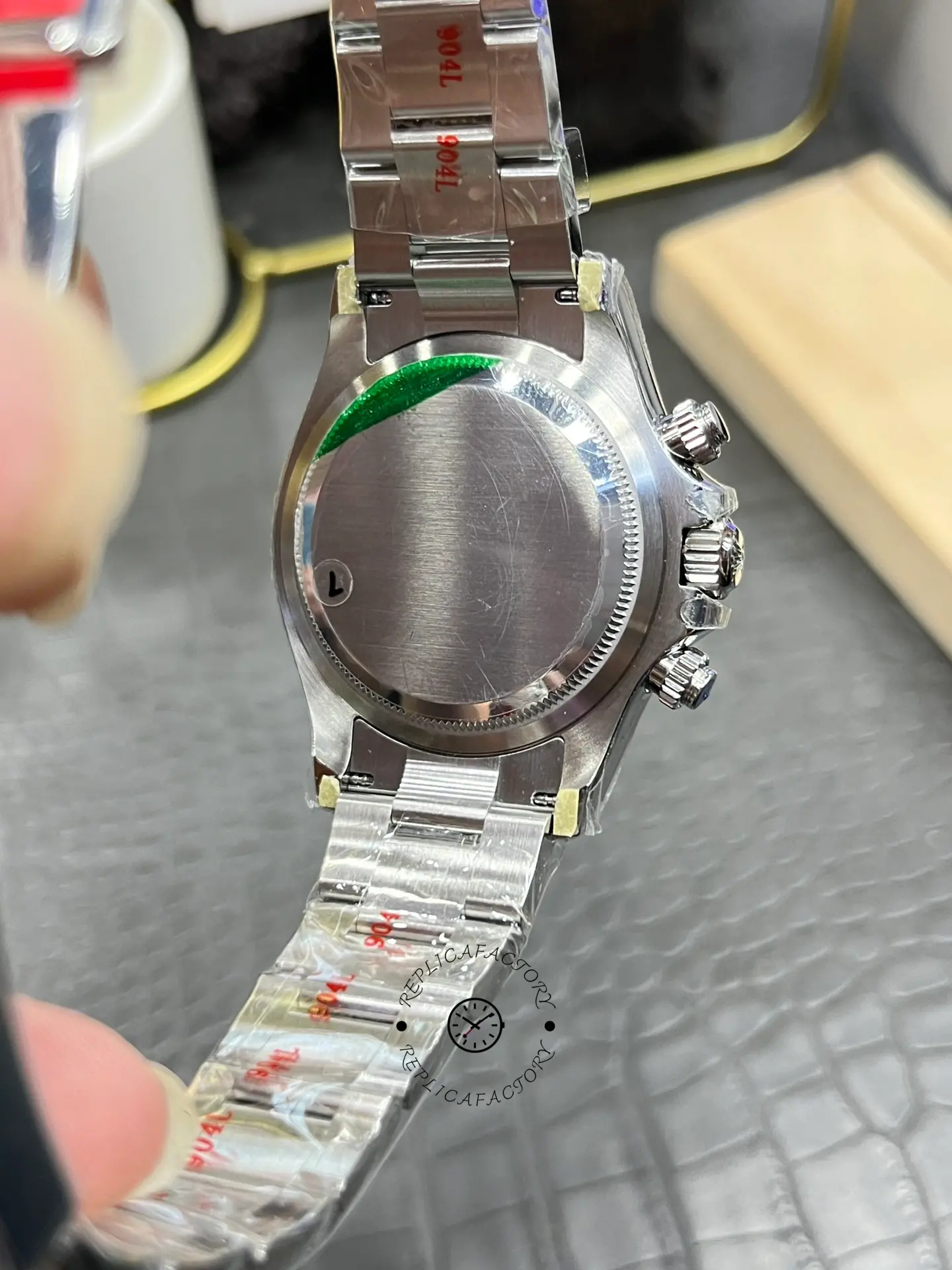 Rolex Daytona M126500LN-0001 case back in hand, smooth back and bracelet attachment.